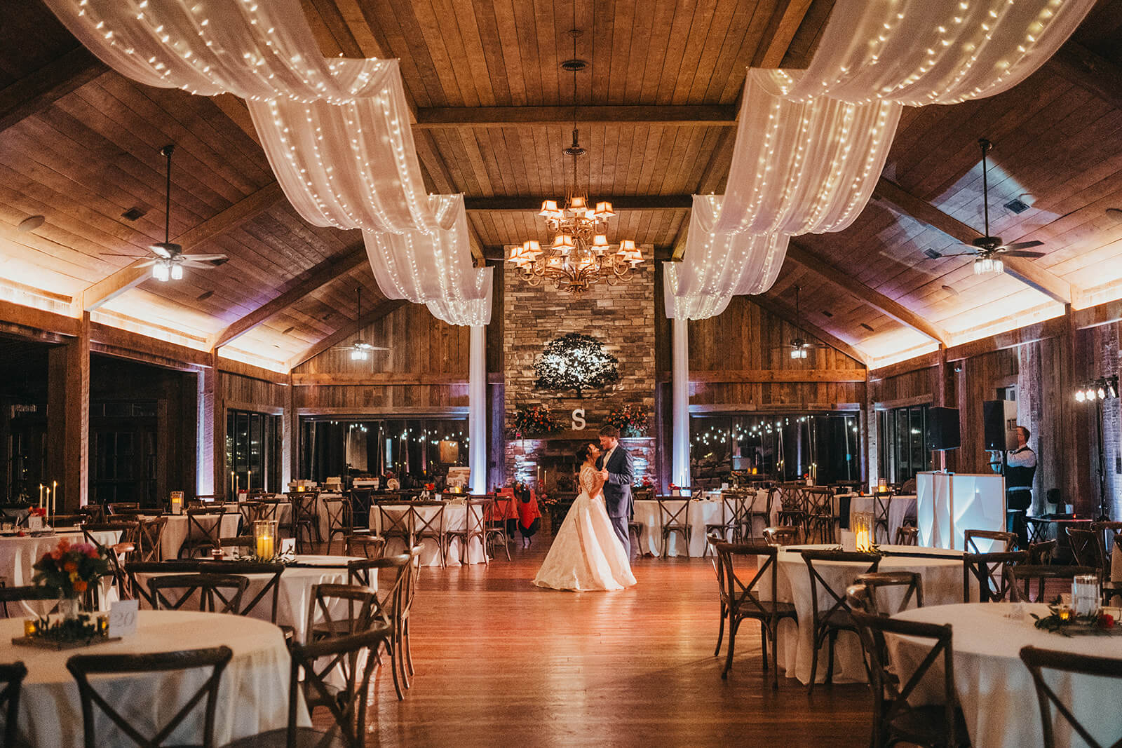 A final dance by a wedding couple at NC venue Experience Oakhaven showcasing the ceiling draping with lights.